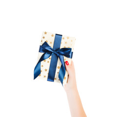 Woman hands give wrapped Christmas or other holiday handmade present in gold paper with blue ribbon. Isolated on white background, top view. thanksgiving Gift box concept