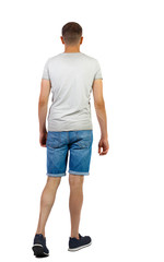 Back view of going handsome man in shorts.