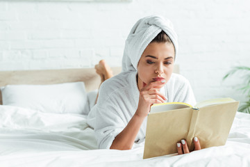 attractive woman in towel and bathrobe reading book at morning