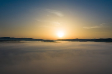 Fototapeta na wymiar Misty sunrise with sunrays over the hills in Transylvania, Romania.