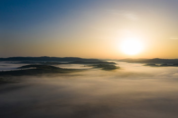 Misty sunrise with sunrays over the hills in Transylvania, Romania.