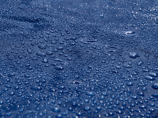 Obraz premium Rain water droplets on blue fiber waterproof fabric. Blue background.
