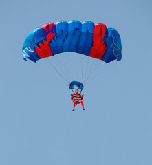 Red and blue parachute with paratrooper in sky