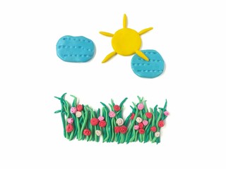 Beautiful sun and blue cloud over on green grasses handmade from plasticine clay are on white background, cute sky natural dough