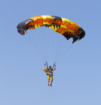 Skydiver under canopy of parachute in blue sky