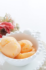 Orange ice cream in white bowl with copy space