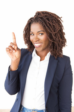 Happy young businesswoman sharing new idea, pointing index finger up. African American business woman standing isolated over white background, looking at camera, smiling. Business idea concept
