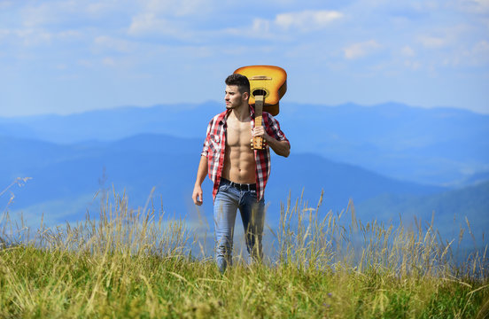 freedom. happy and free. cowboy man with bare muscular torso. acoustic guitar player. country music song. sexy man with guitar in checkered shirt. hipster fashion. western camping and hiking