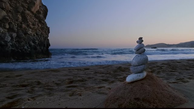 Balance stones on beach at sunset. Rock and sea waves in background. Concept of zen, relax, meditation, fragility