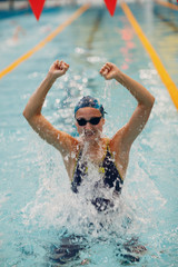 Young woman swimmer portrait joy rejoices in victory in swimming competitions in swimming pool. Win...
