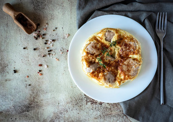 Omelette with meat meatballs on a white plate on a gray background