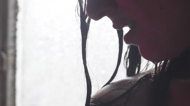 profilo di donna in doccia con capelli bagnati e gocce d'acqua