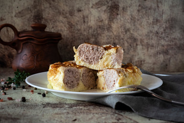 Delicious omelet with meat meatballs on a white plate on an ancient gray background