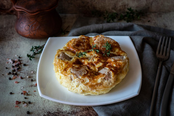 Omelette with meat meatballs on a white plate on a gray background