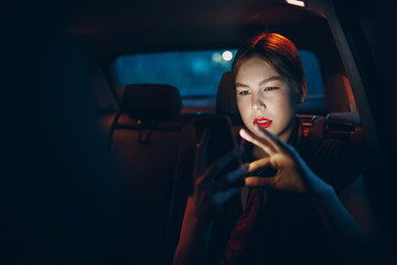 Young woman sitting in back seat of car vehicle with mobile phone. Taxi concept.