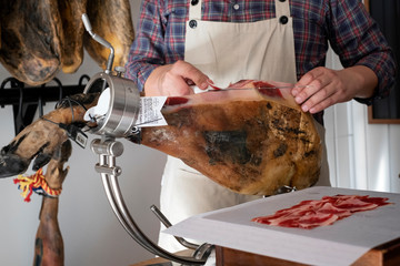 man cutting ham with a knife in a ham holder