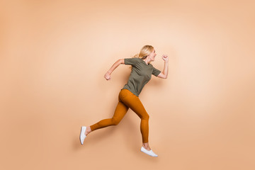 Fototapeta na wymiar Full length profile photo of crazy lady jumping high speed race marathon participant competitive mood rushing sales wear green t-shirt yellow trousers isolated beige color background