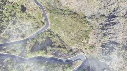 Windy road across the mountain, overhead aerial view in monochrome, downward pointing drone camera