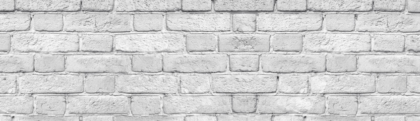 Light gray brick wall close-up wide texture. Old rough stone block whitewashed background