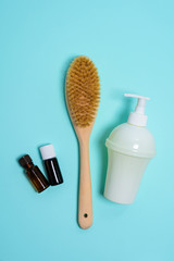 Anti-cellulite brush for dry body massage, aromatherapy soap in a white bottle on a blue background. Lymphatic drainage body massage. the view from the top