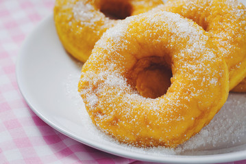 Bakery sweet donuts sprinkled with sugar powder on white plate on napery background