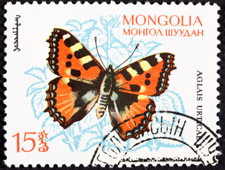 Fototapeta na wymiar Stamp from mongolia with a photo of a beautiful single butterfly on paper