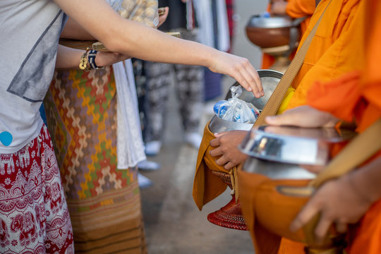 The people are offering food to monks by offering into the alm bowl in the morning. The design on the robe or dress are very normal printing and can be seen  in every shop or every place. 