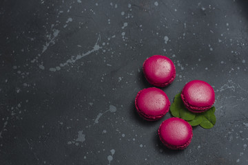 Fototapeta na wymiar Colorful french macarons cookies (macaroons) on a dark background. Dessert for served with tea or coffee break. Holiday gift for women.