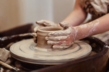 Child working on the potter's wheel. Hands sculpts a cup from clay.