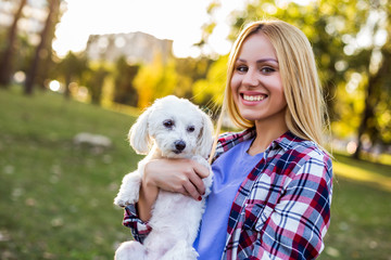 Beautiful woman spending time with her Maltese dog outdoor.	