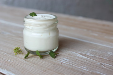 Organic cosmetics. Cream with green leaves on the background of boards.