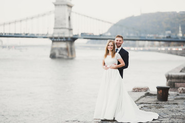 Elegant stylish happy blonde bride and gorgeous groom on the background of a beautiful river in the mountains