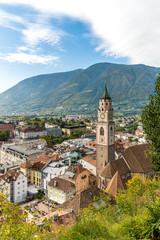 Ansicht alte Stadt Meran in Südtirol mit Bergen, blauem Himmel und Pfarrkirche St. Nikolaus