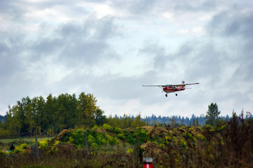 Fototapeta na wymiar The red light plane lands over the field.