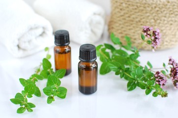 Oregano essential oil, fresh herbs, white towels, phytotherapy, natural cosmetics.