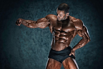 Fototapeta na wymiar Handsome Muscular Bodybuilder Flexing Muscles