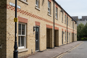 Detailed image of newly build terraced houses seen in a market town in the UK. The road appears to be empty and double yellow lines can be seen.