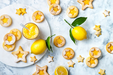 Linzer Christmas cookies filled with lemon curd and dusted with sugar on white marble board