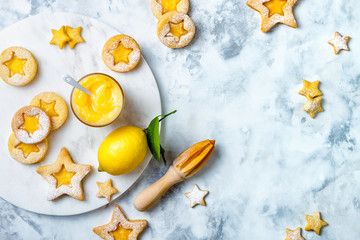 Linzer Christmas cookies filled with lemon curd and dusted with sugar on white marble board
