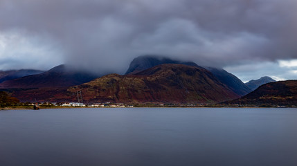 a view of ben nevis near fort william shot in winter as wintry storms approach the summit showing calm waters and cloudy stormy skies as seen from corpach beach