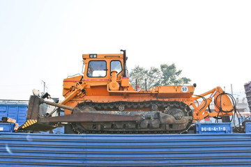 Construction machinery - yellow bulldozer on the platform of a freight railway car. Cargo transit.