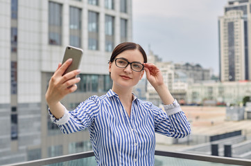 Intelligent business woman with brown hair in glasses in a blue and white striped shirt with white...