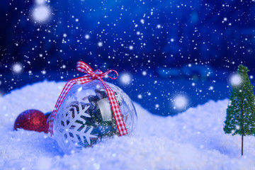 Christmas background with Christmas balls on snow over fir-tree, night sky and moon. Shallow depth of field. Christmas background. Fairy tale. Macro. Artificial magic dreamy world.