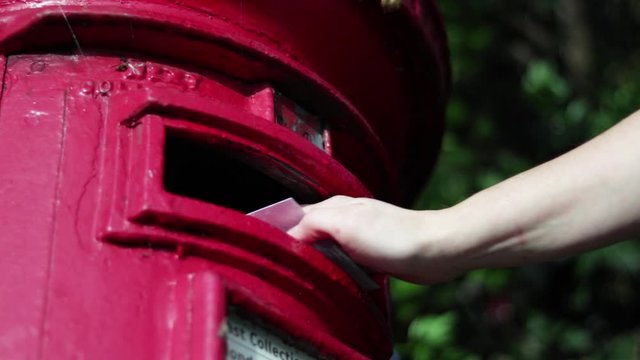 Slow Motion Of White Woman Posting Letter Into English Red Postbox