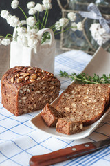Freshly baked rye bread with seeds and raisins on sourdough without yeast on a white plate with a knife for cutting. Homemade cake. Fermentation process