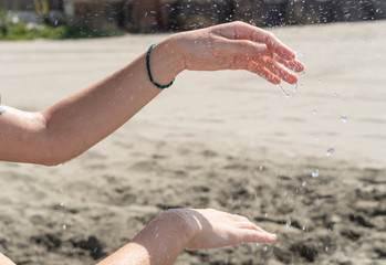Fototapeta na wymiar Hands playing with falling water on the beach