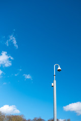 Isolated view of a newly installed dome CCTV camera seen on a tan metal pole, located outside government offices in central London.