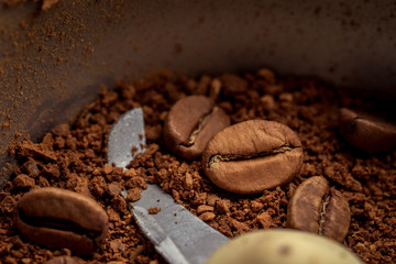 Macro photo of freshly ground coffee in electric coffee grinder. In one half whole grains of...