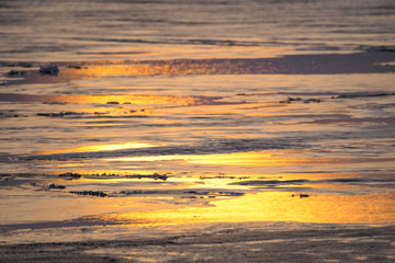 Fototapeta na wymiar spring ice melts on the lake. reflection of sunset in thawed patches on water. Dramatic scene of natural background. landscape in the evening on the lake.