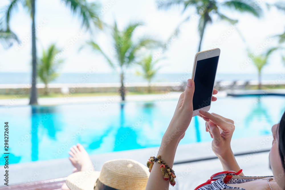 Wall mural young woman sitting on outdoor hand holding mobile smartphone black screen with copy space for text 